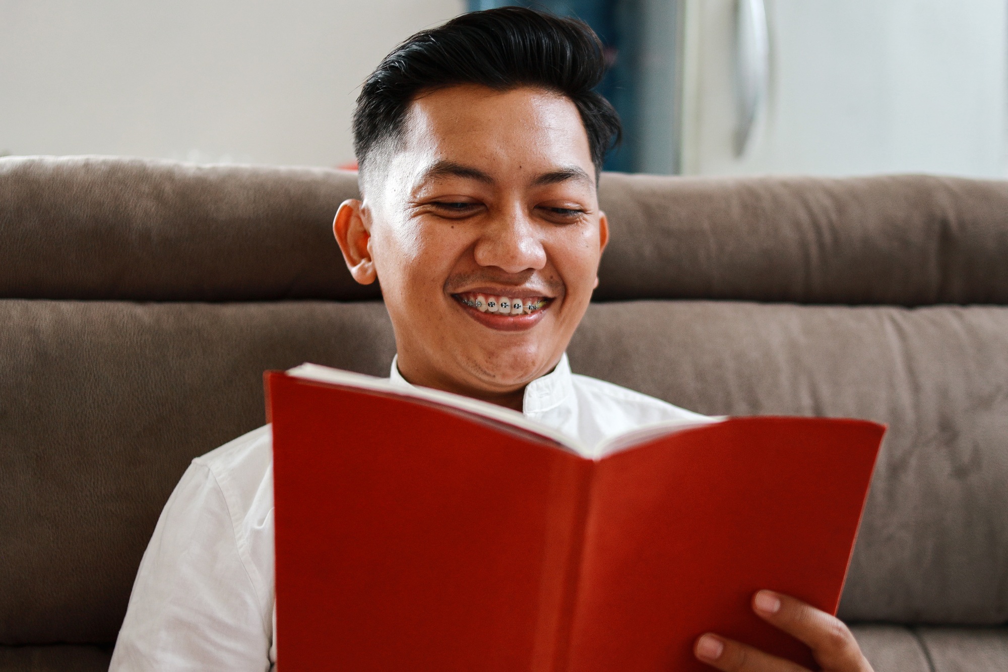 Adult Male With Braces And Reading Book