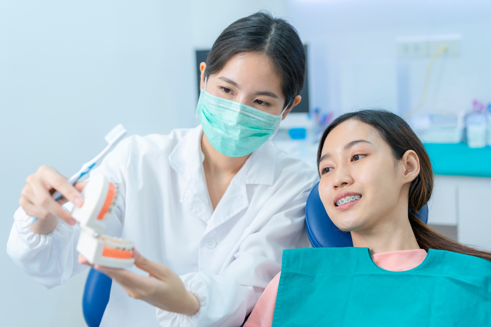 Asian woman listening dentist explaining about teeth brushing for people have orthodontic.