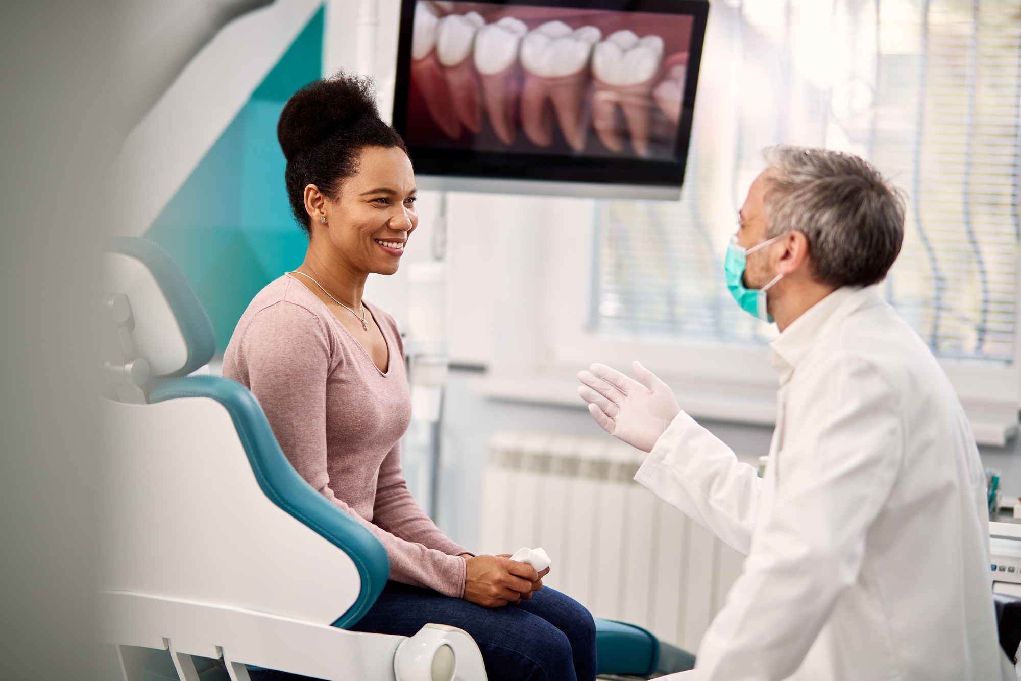 Happy black woman talking to her orthodontist at dentist's office.