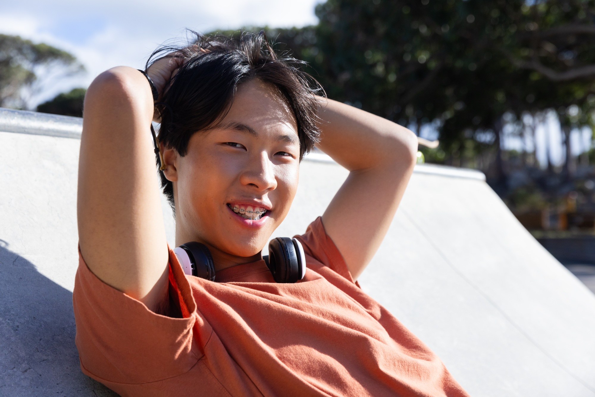 Outdoors, Relaxing at skatepark, asian teenage boy with braces and headphones smiling