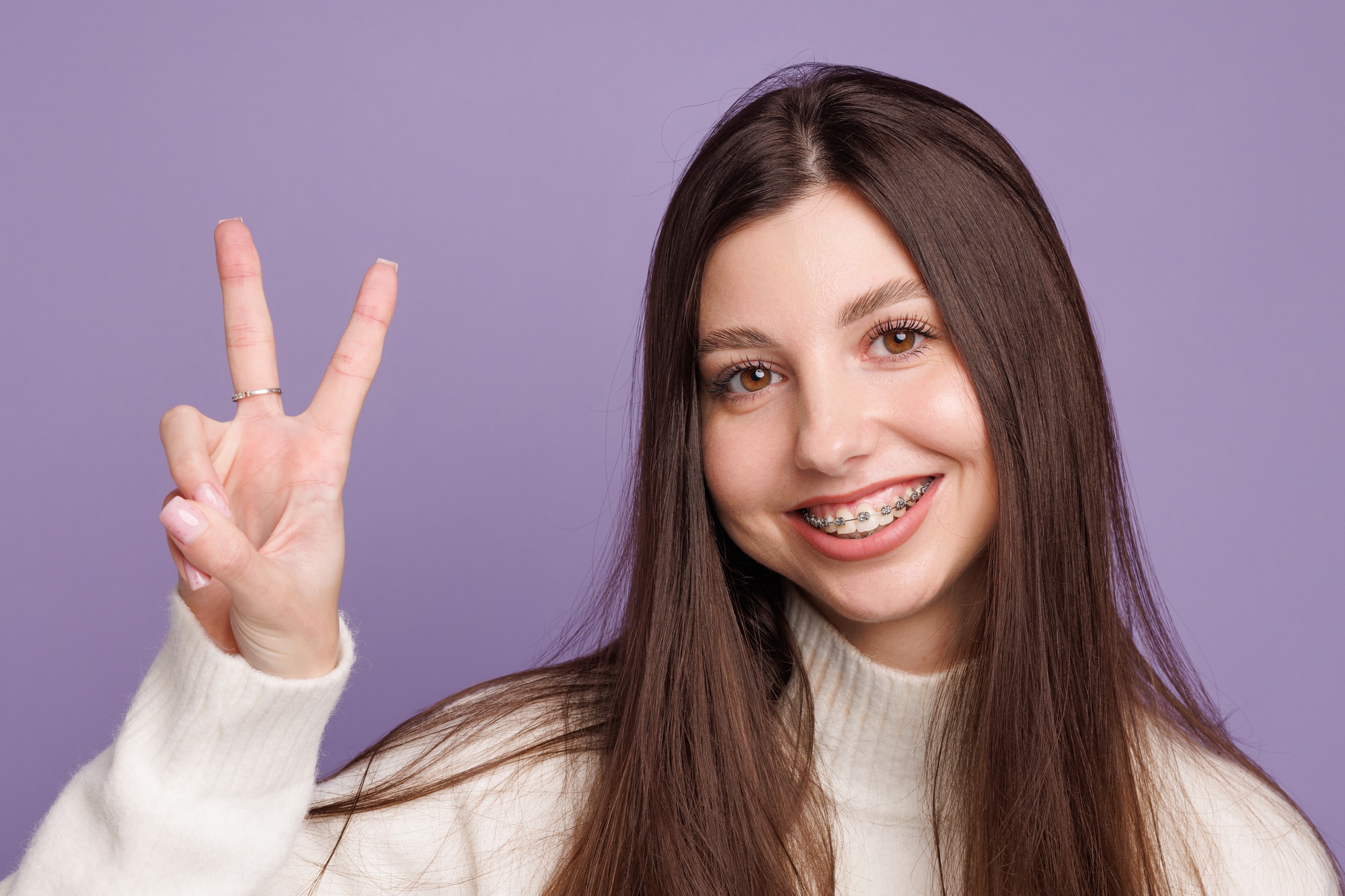 portrait of a girl with braces, woman happy with braces shows ok sign