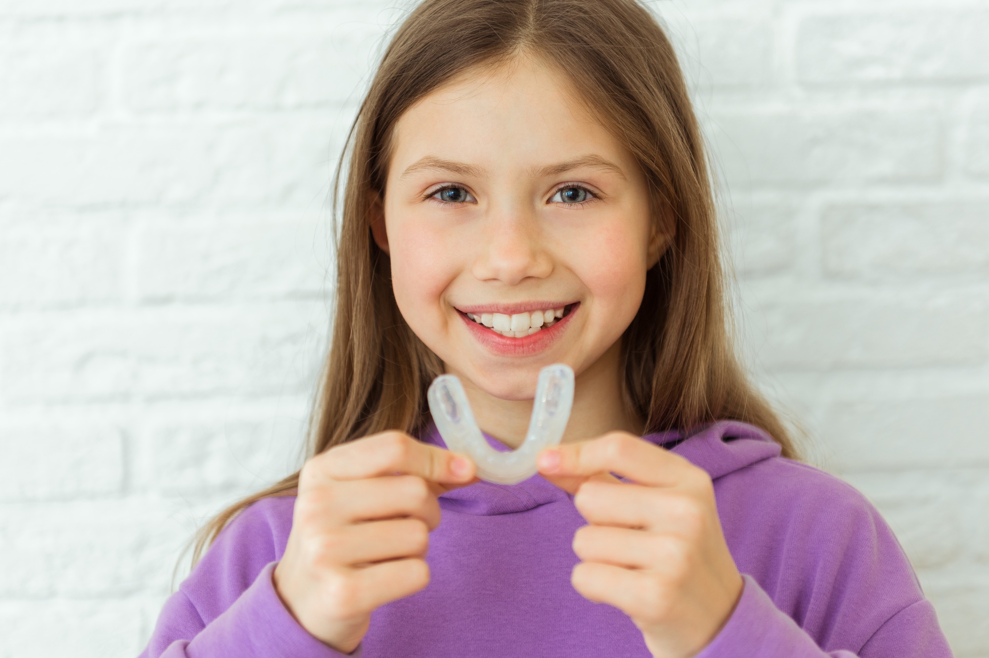 Positive child girl holds mouth guards for her teeth. Orthodontic silicone transparent. Dental care