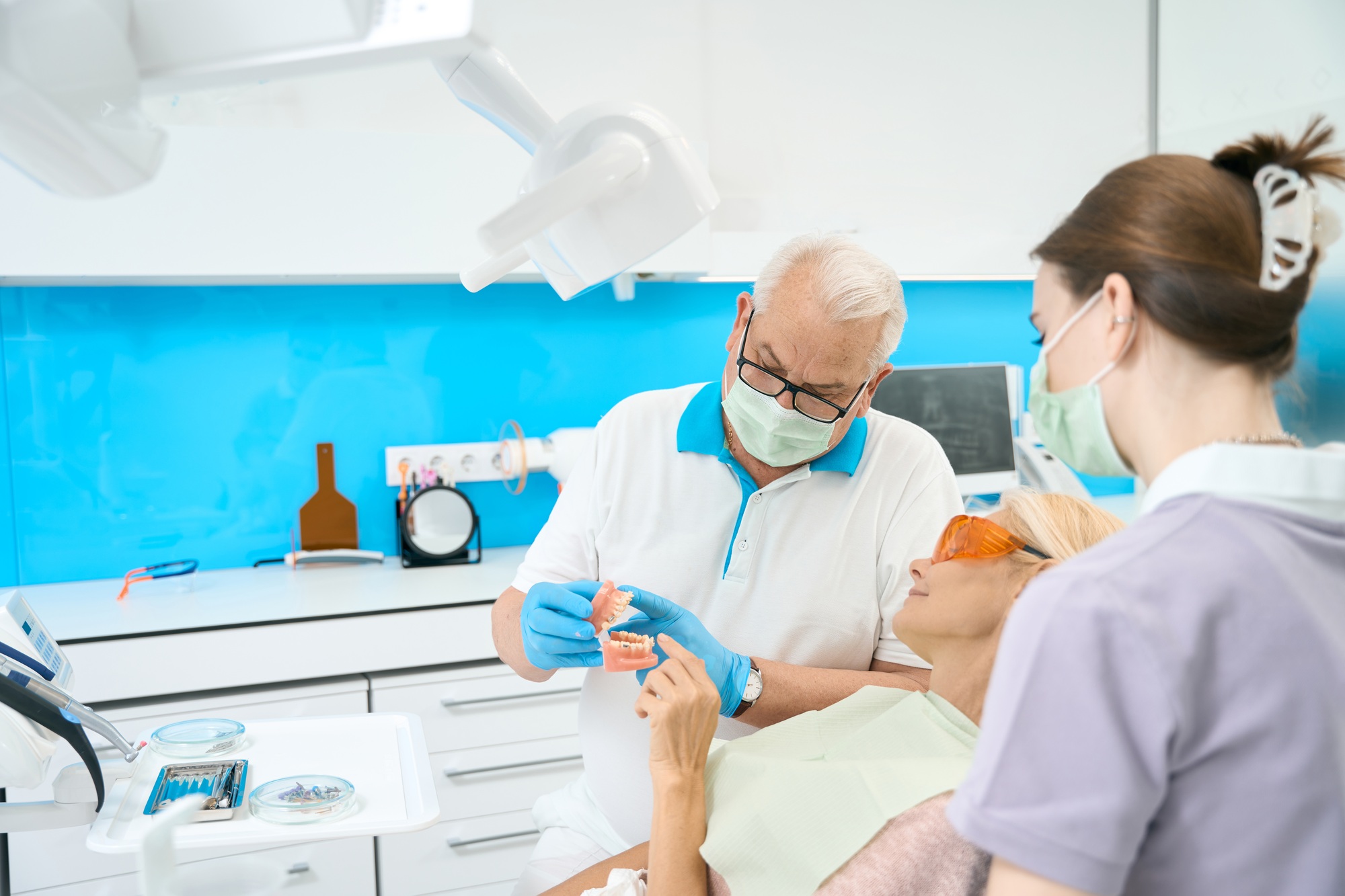 Seriously orthodontist with orthodontic bracket in hands talking with patient