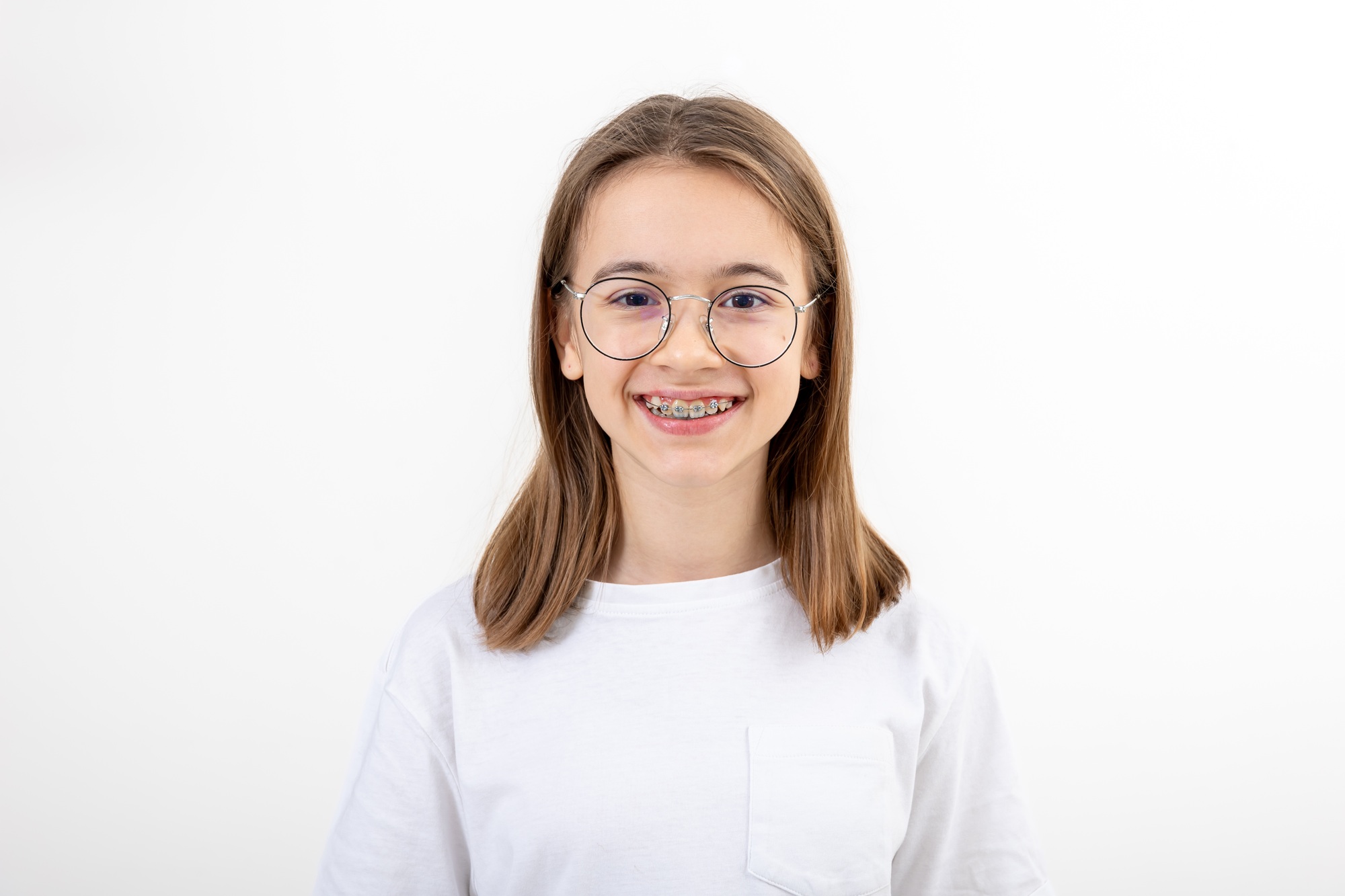 Teenage girl wearing glasses and braces on her teeth isolated on white.